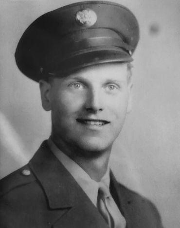 Black and white portrait of a smiling soldier in uniform and cap.