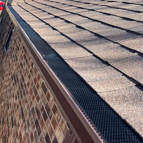 Close-up of a roof gutter with a protective guard installed along the edge.
