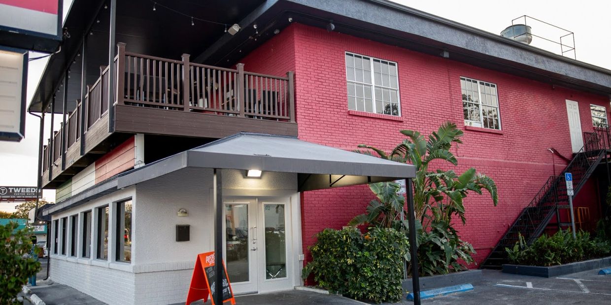 Two-story building with red and gray exterior and outdoor balcony.