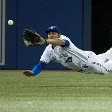 Baseball player diving to catch a ball mid-air.