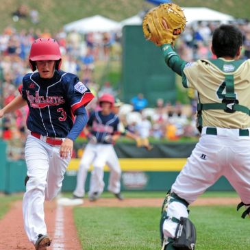 Young baseball player running towards home plate while catcher prepares to catch ball.