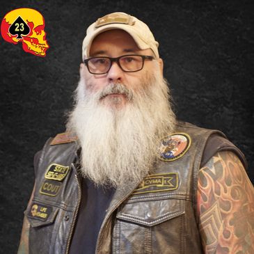 Bearded biker with tattoos and patches on leather vest.