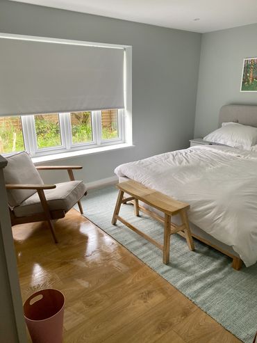 queen-sized bed with wooden bench and armchair with wastebasket