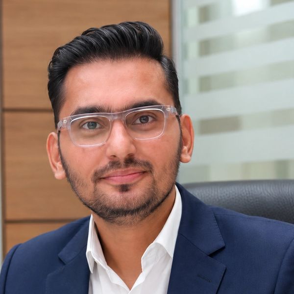 Confident man in glasses and a navy blue suit smiling at the camera.