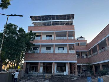 A multi-story brick building under construction with trees around.