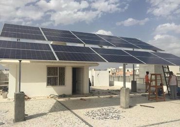 Solar panels installed on a rooftop with two people working nearby.