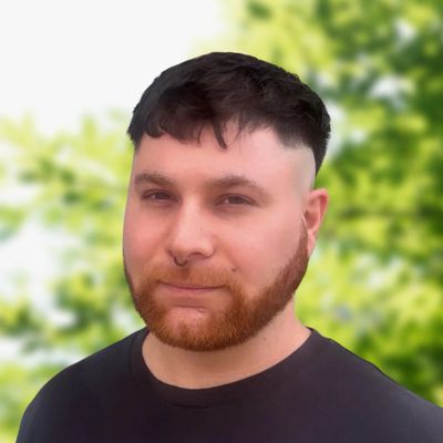 Portrait of a man with red beard and black hair outdoors.