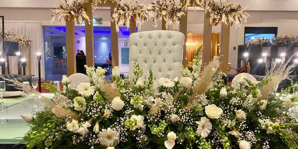 Elegant white floral arrangement with a tufted chair and decorative backdrop.