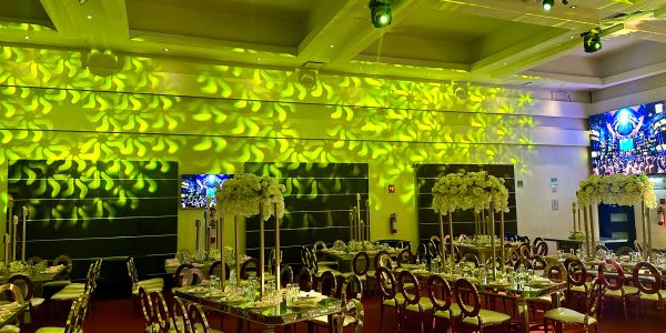 Elegant banquet hall with floral centerpieces and green lighting.