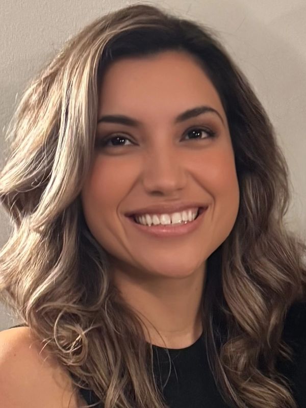 A woman with wavy hair smiling warmly at the camera.
