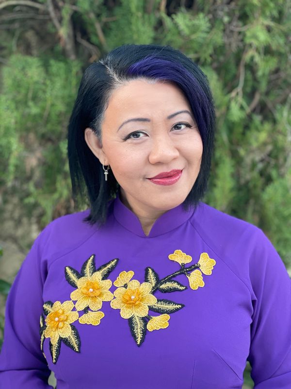 Woman in a purple dress with yellow floral embroidery.