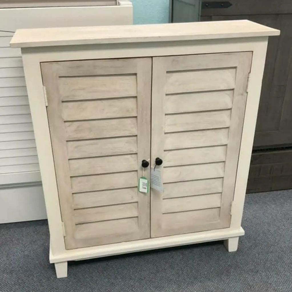 Rustic two-door wooden cabinet with slatted design and black knobs.