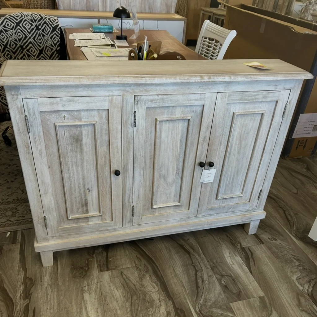 Rustic wooden cabinet with a distressed white finish and three paneled doors.