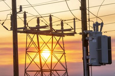 Sunset behind electrical power lines and transformer poles.