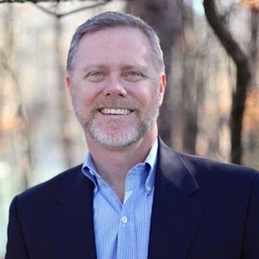 Smiling middle-aged man in a suit outdoors.
