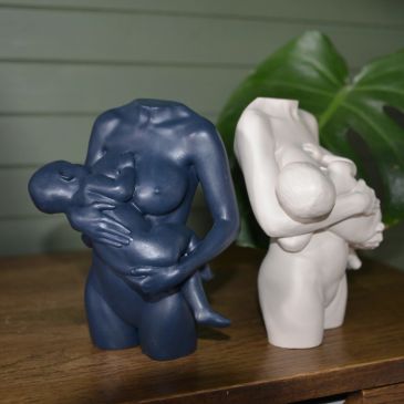 Two headless sculptures of a mother breastfeeding a child.