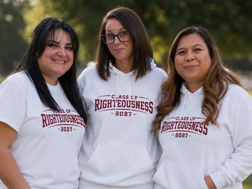Three women wearing matching "Class of Righteousness 2027" shirts and hoodies.