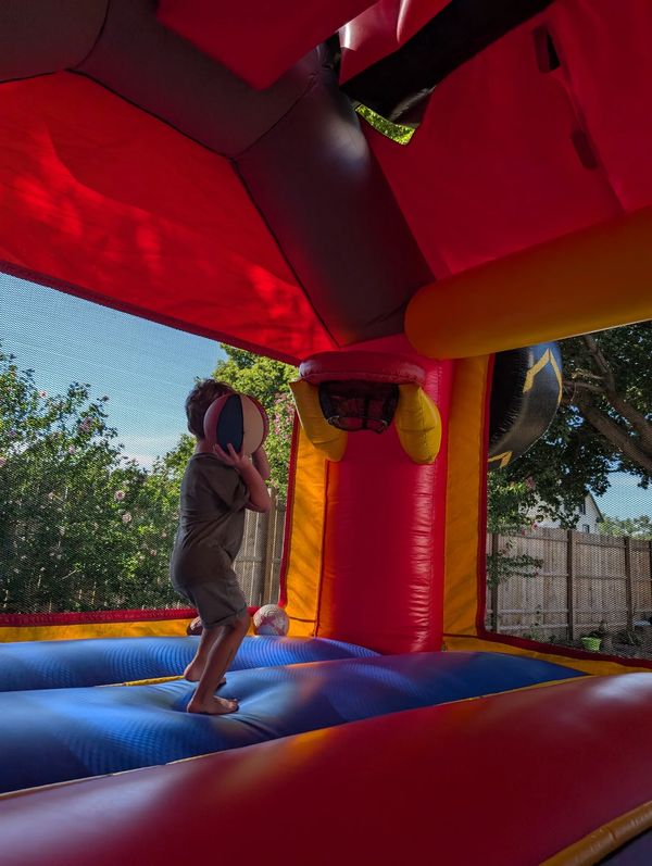 A child preparing to shoot a basketball inside a colorful bounce house.
