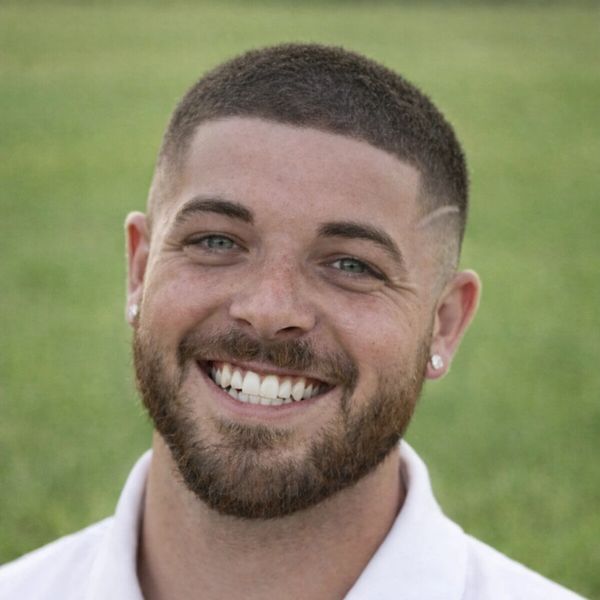 Smiling young man with beard and earrings outdoors.
