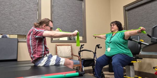 Physical therapy session with resistance bands for arm exercises.