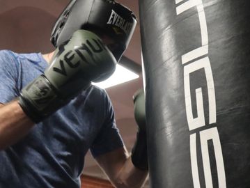Man punching a punch bag in a boxing gym
