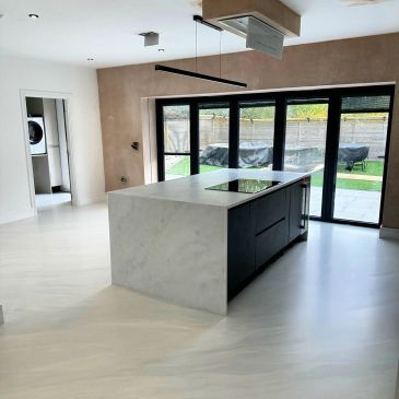 Modern kitchen with marble island and large glass doors.