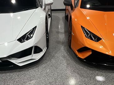 Front view of two Lamborghini cars in white and orange.