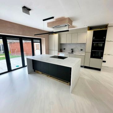 Modern kitchen with marble island and large glass doors.