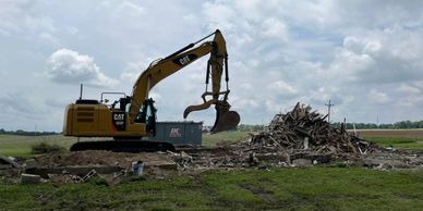 Excavator demolishing building and loading into roll off dumpster