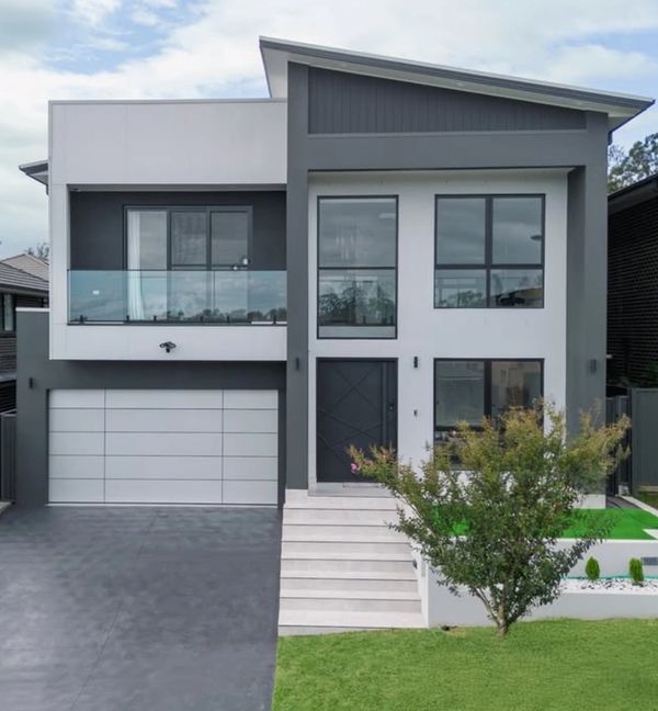 Modern two-story house with large windows and a sleek design.