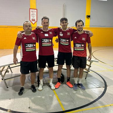 Four men in matching sports jerseys posing in a gymnasium.