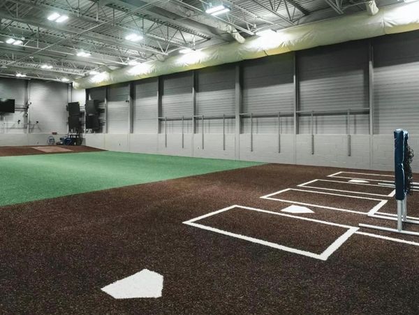 Indoor baseball training facility with pitching areas and batting cages.