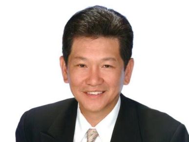 一位穿着黑色西装的男性微笑着。