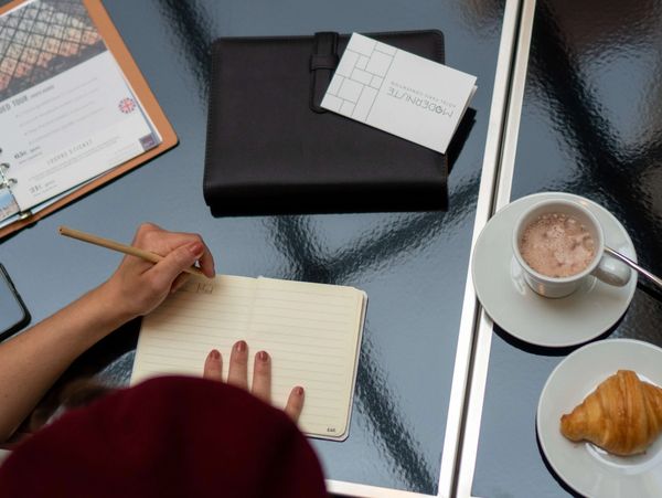 Toma cenital de una persona sentada en una mesa escribiendo en una libreta 