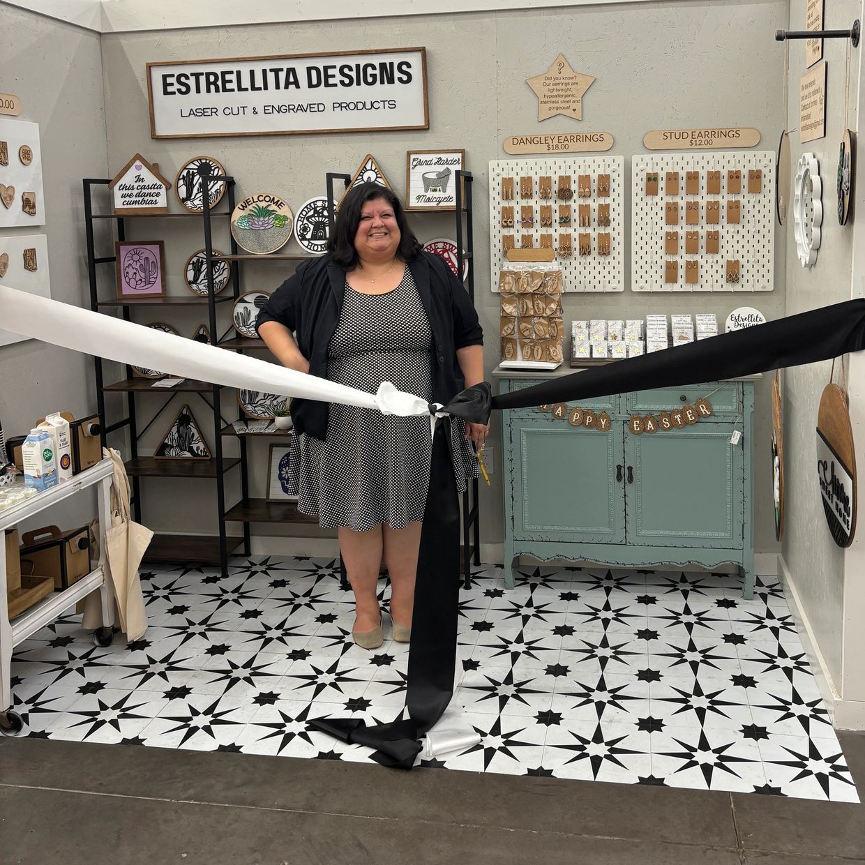 Woman standing in front of Estrellita Designs booth with laser-cut products.