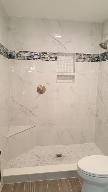 shower tiled with marble look tile and glass accents
