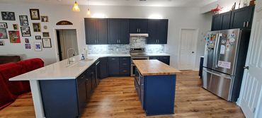 Modern kitchen with navy blue cabinets and wooden flooring.