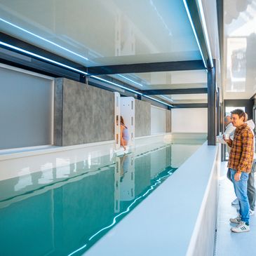 Indoor swimming pool with a child climbing out and men observing.
