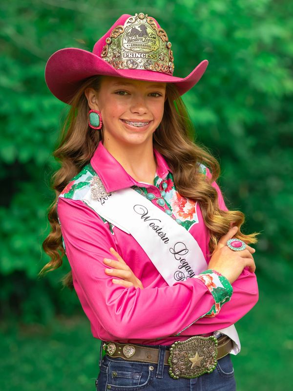 Young girl in pink cowboy attire with a sash and crown.