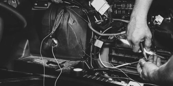 Hands fixing wires in a vehicle engine.