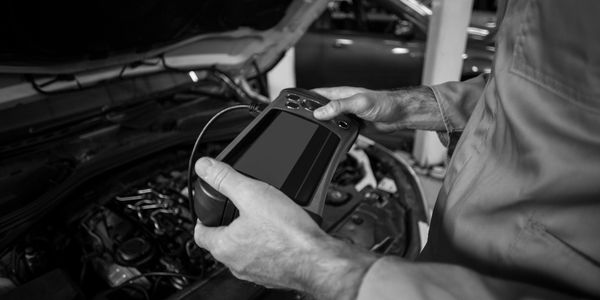 Mechanic using diagnostic tool on car engine.