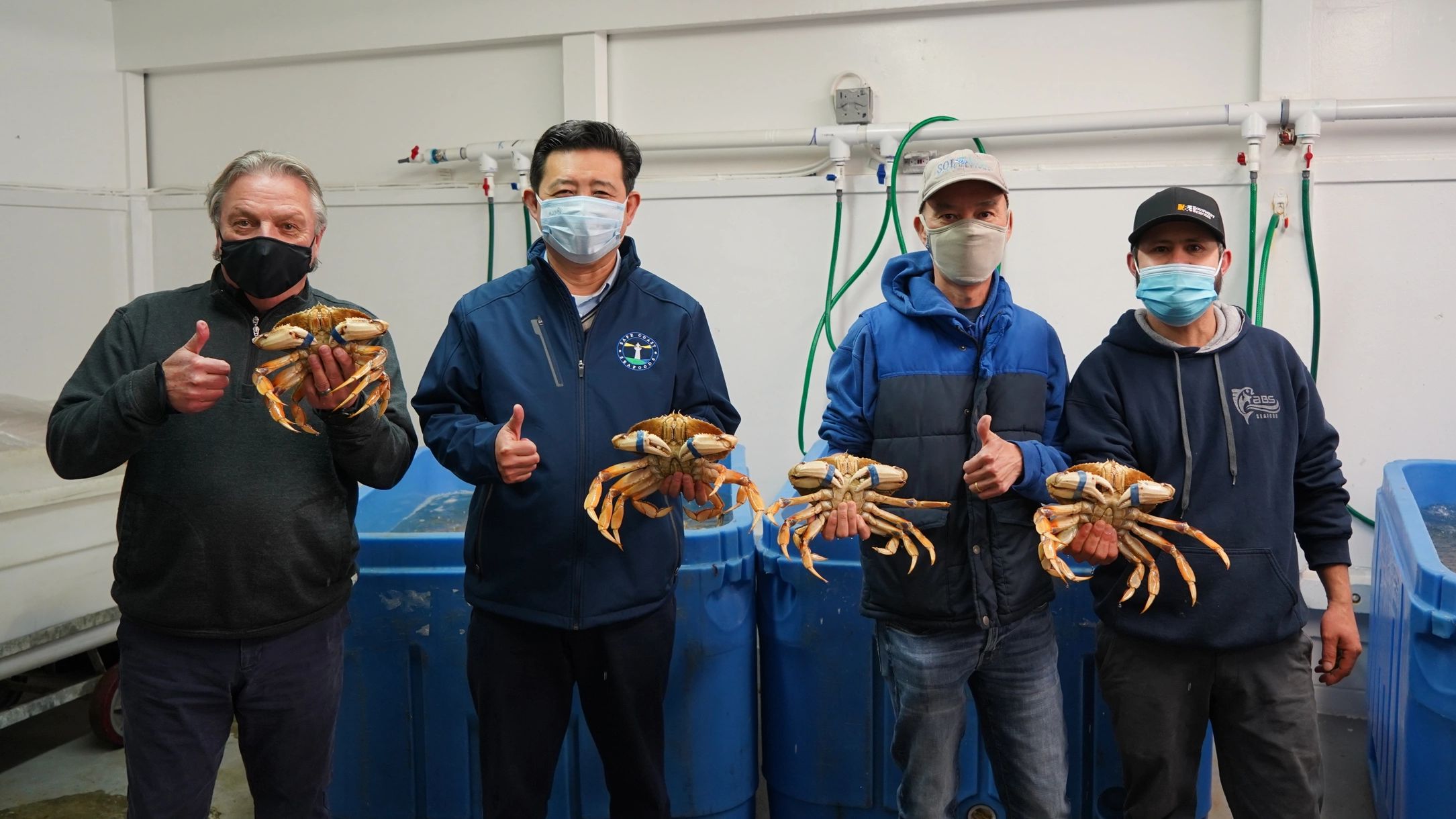 4 men holding dungeness crabs
