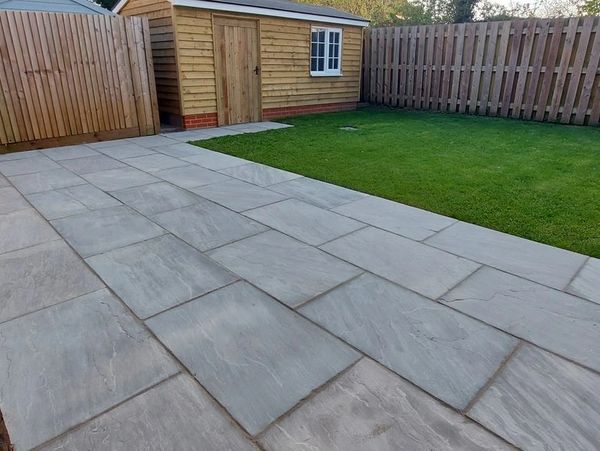Backyard with stone patio and green lawn.