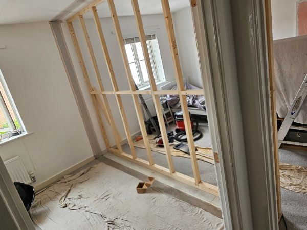 Room under renovation with wooden frame and tools.