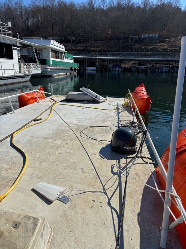Boat deck with equipment and orange flotation devices docked at a marina.