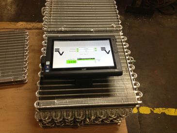 A touchscreen device placed on top of stacked industrial metal coils.