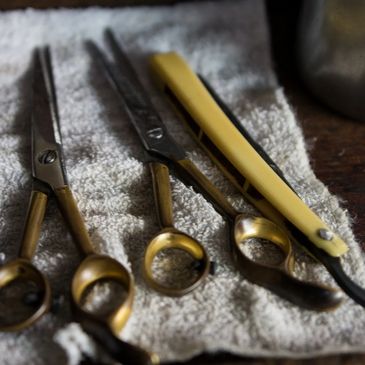 Vintage barber scissors and a straight razor on a white towel.
