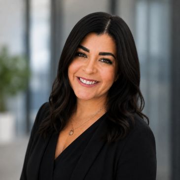 Professional woman with dark hair smiling in a business setting.