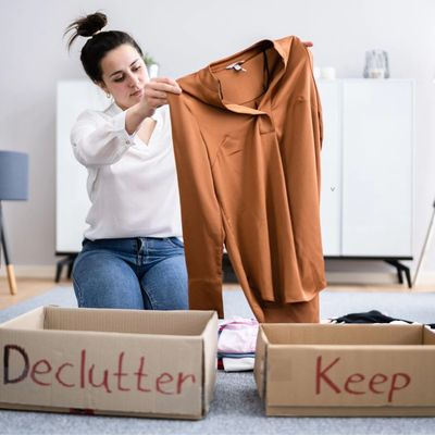 Woman holding shirt, deciding to keep, donate, or give away.