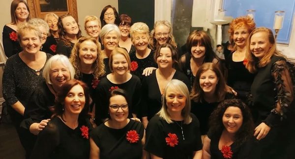 Vocal Infinity dressed in coordinated black outfits with red flower accessories. 